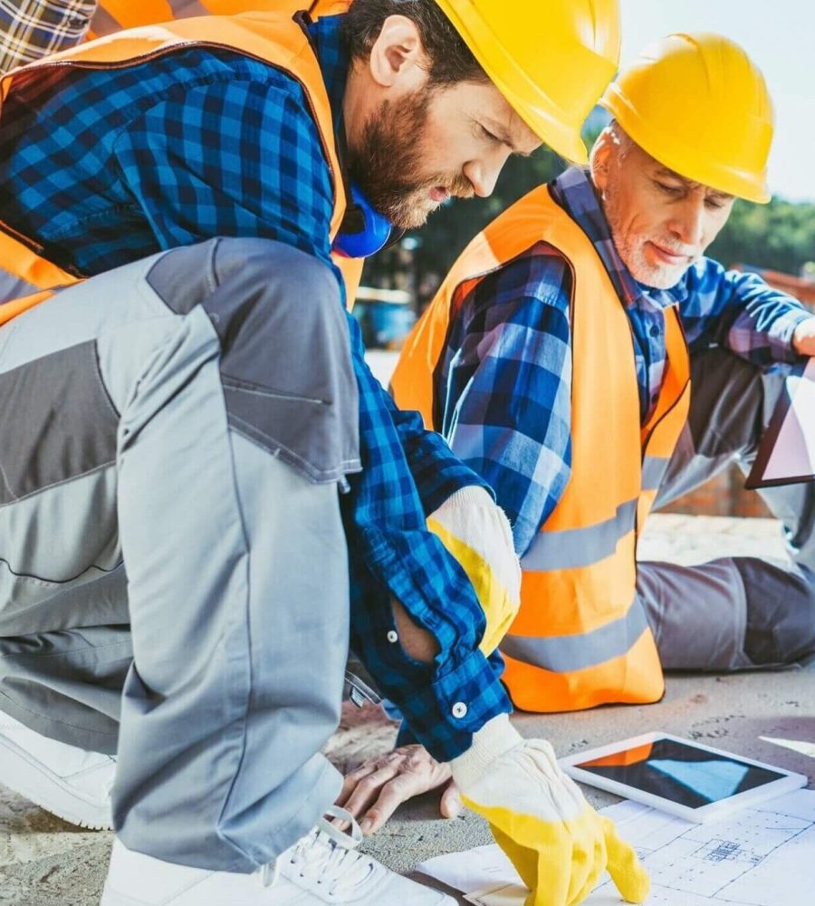 handsome-construction-workers-sitting-on-concrete-at-construction-site-discussing-building-plans-1.jpg